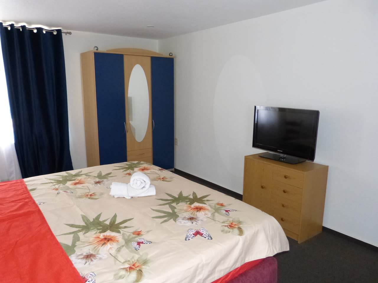 Zweites Doppelzimmer mit Kleiderschrank mit Spiegeltür und Kommode mit Fernseher